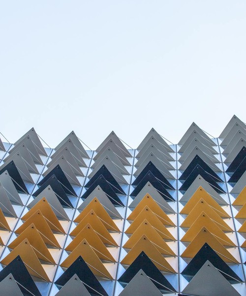 Low angle view of a contemporary facade featuring geometric triangle patterns.